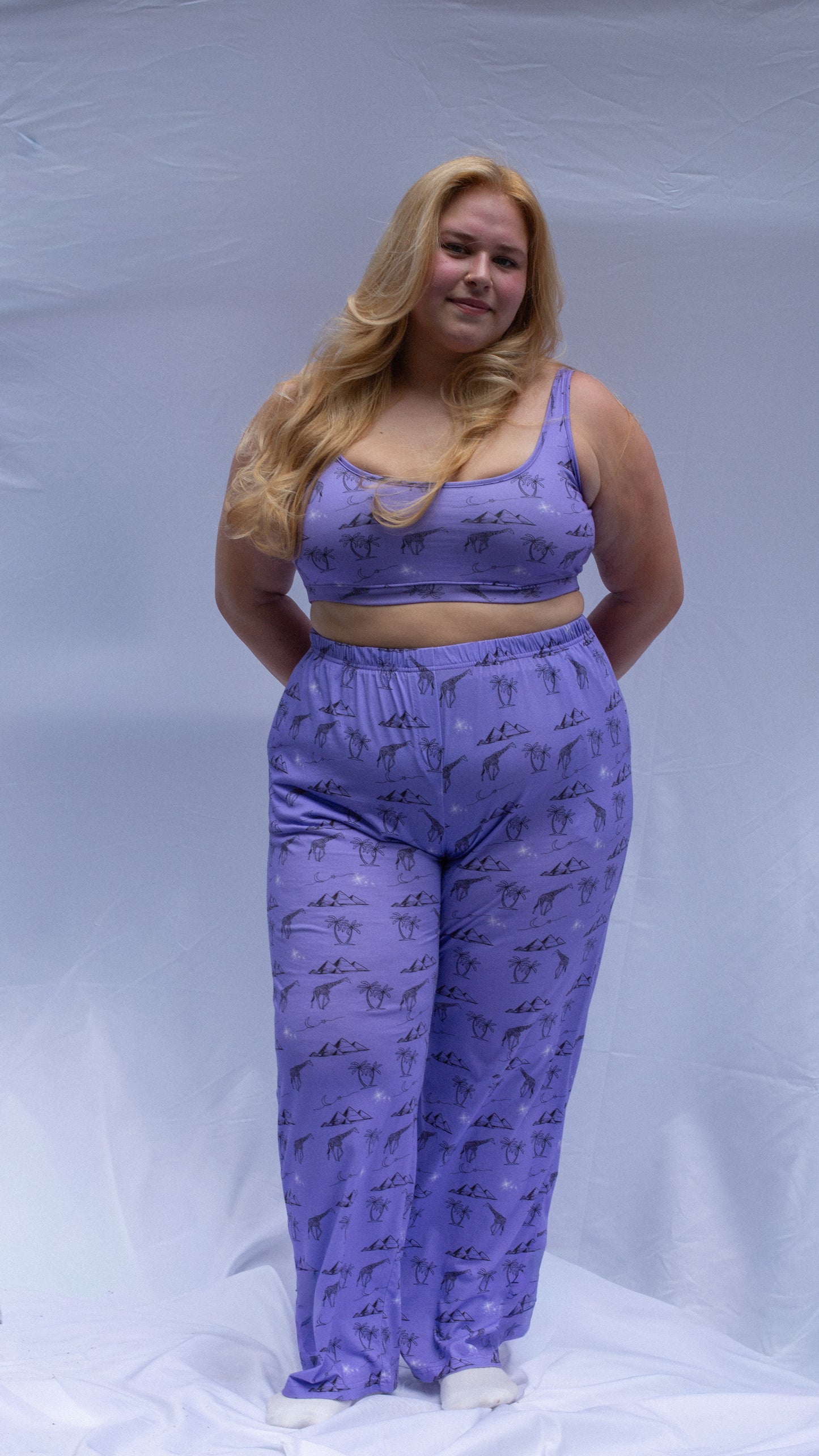 Woman wearing a purple outfit with animal prints on a plain background