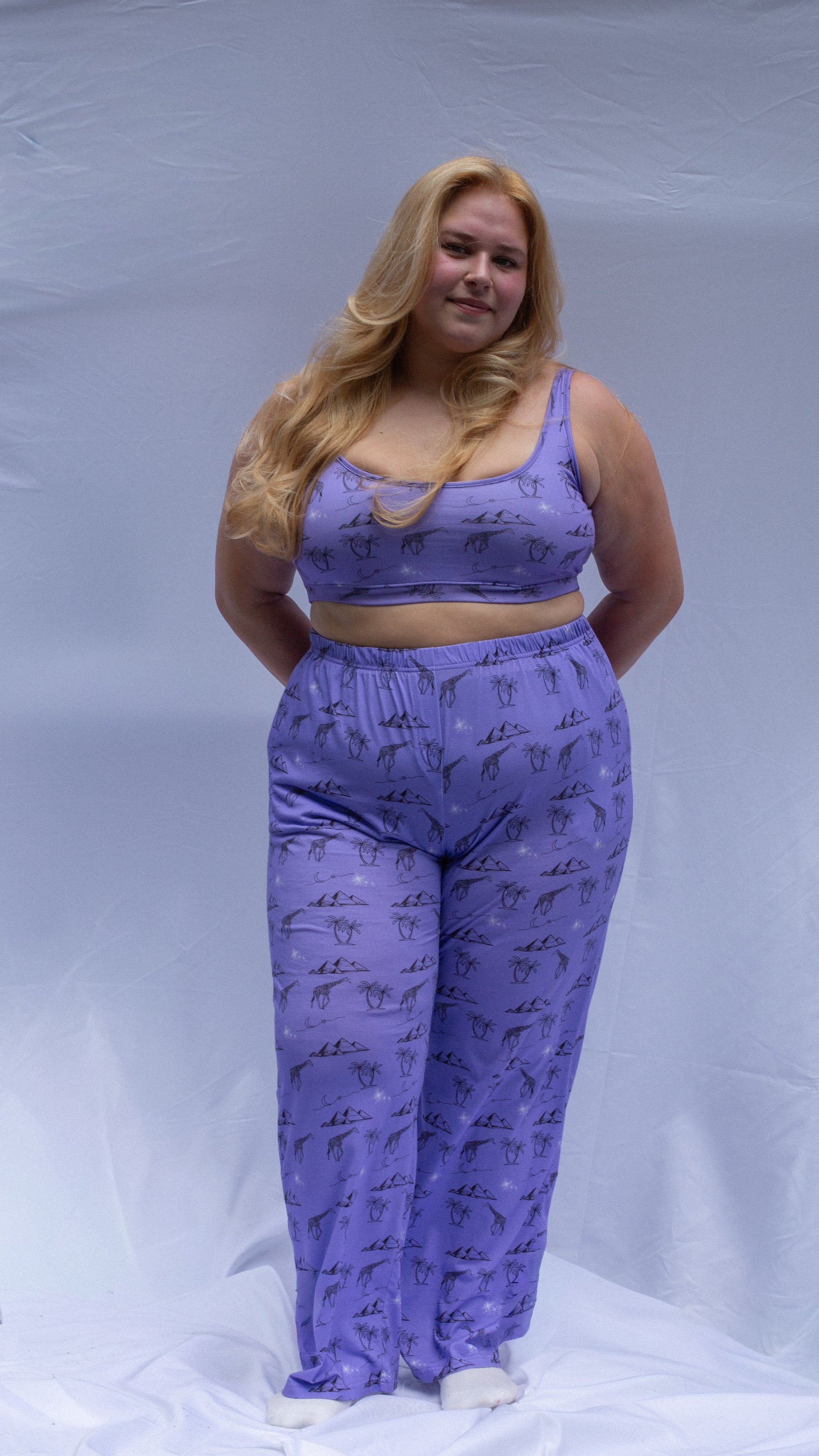 Woman wearing a purple outfit with animal prints on a plain background