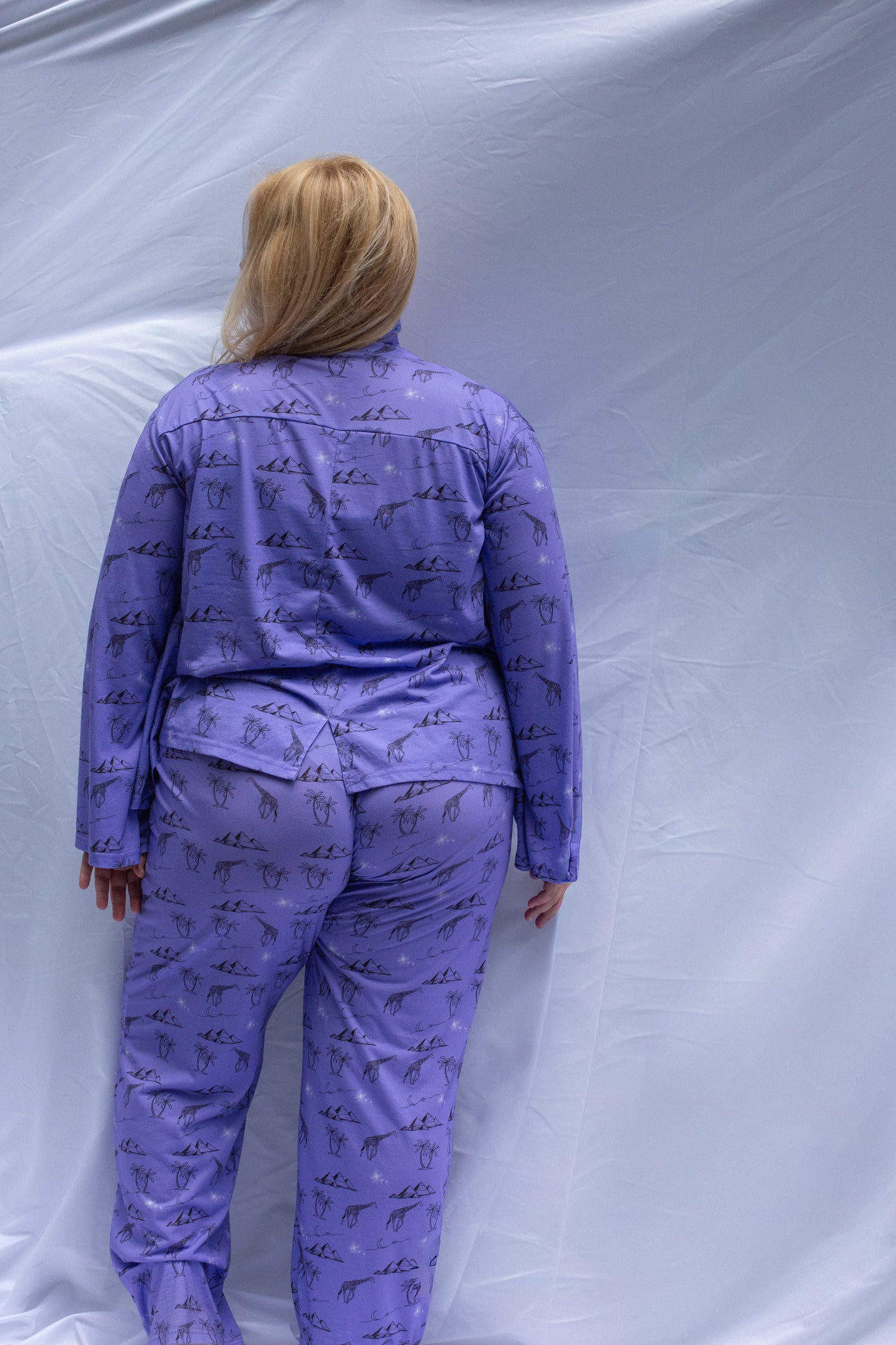 Person wearing a purple pajama set with a pattern against a plain background